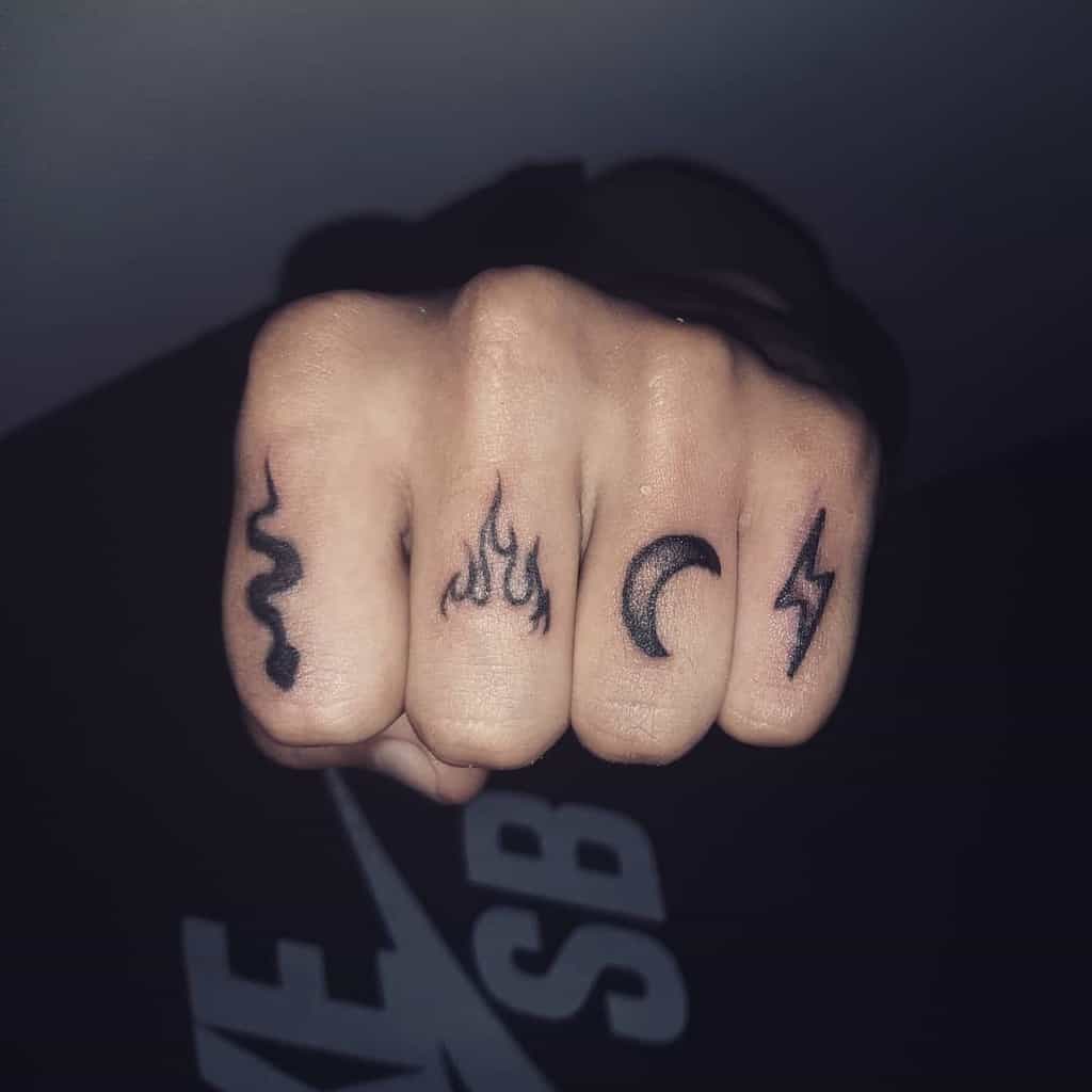 Closed fist with tattoos: snake, fire, crescent moon, and lightning bolt on fingers