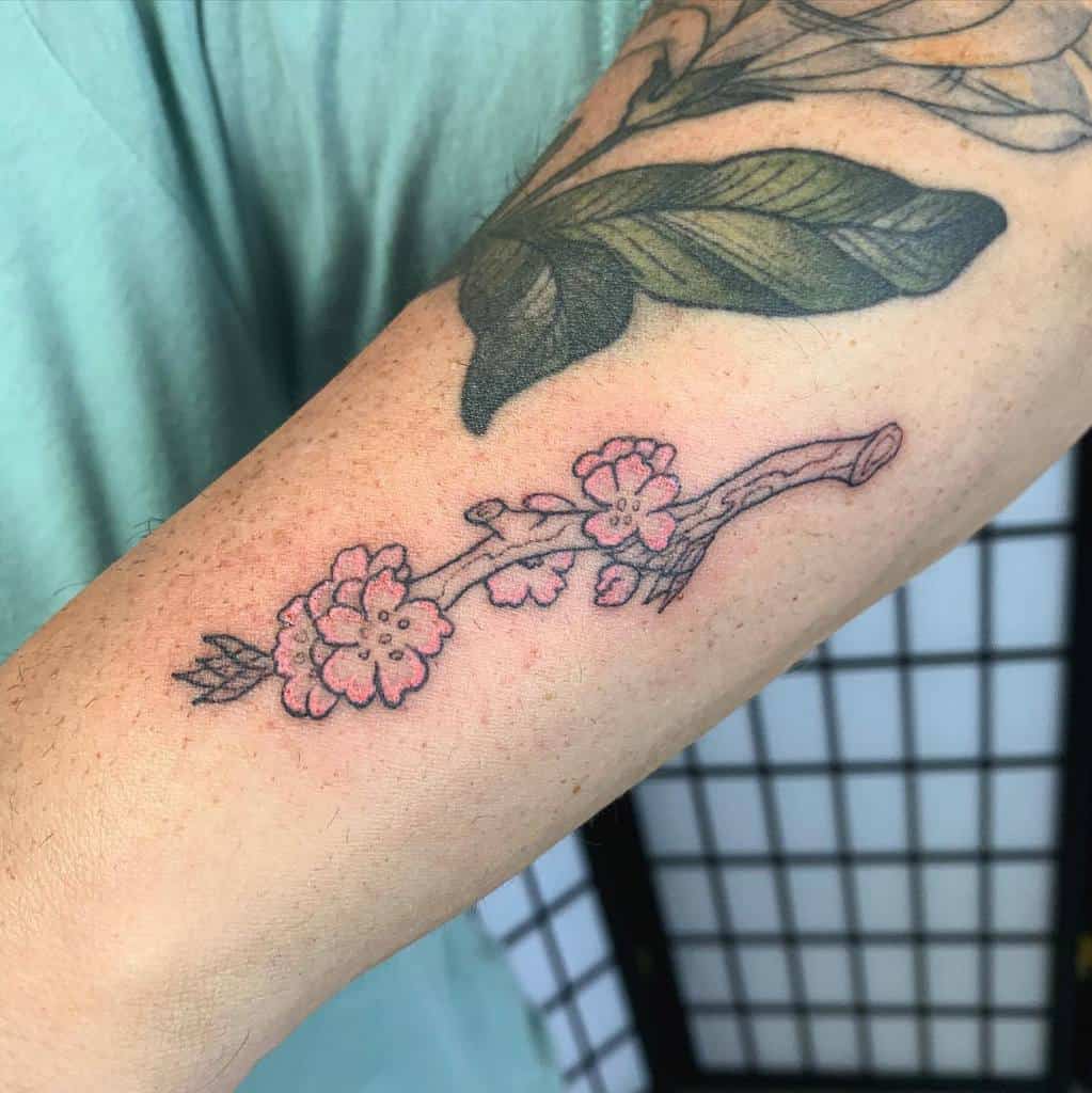 Arm tattoo of delicate pink cherry blossoms beautifully arranged on a graceful branch