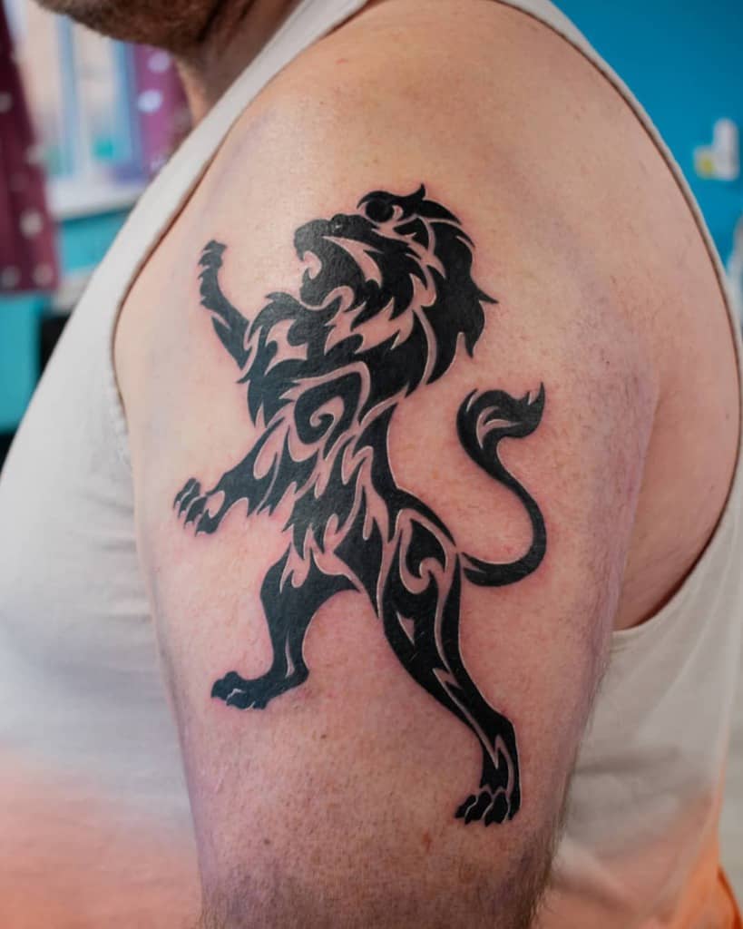 Tribal lion tattoo artfully inked on a person's upper arm, showcasing intricate patterns and bold lines