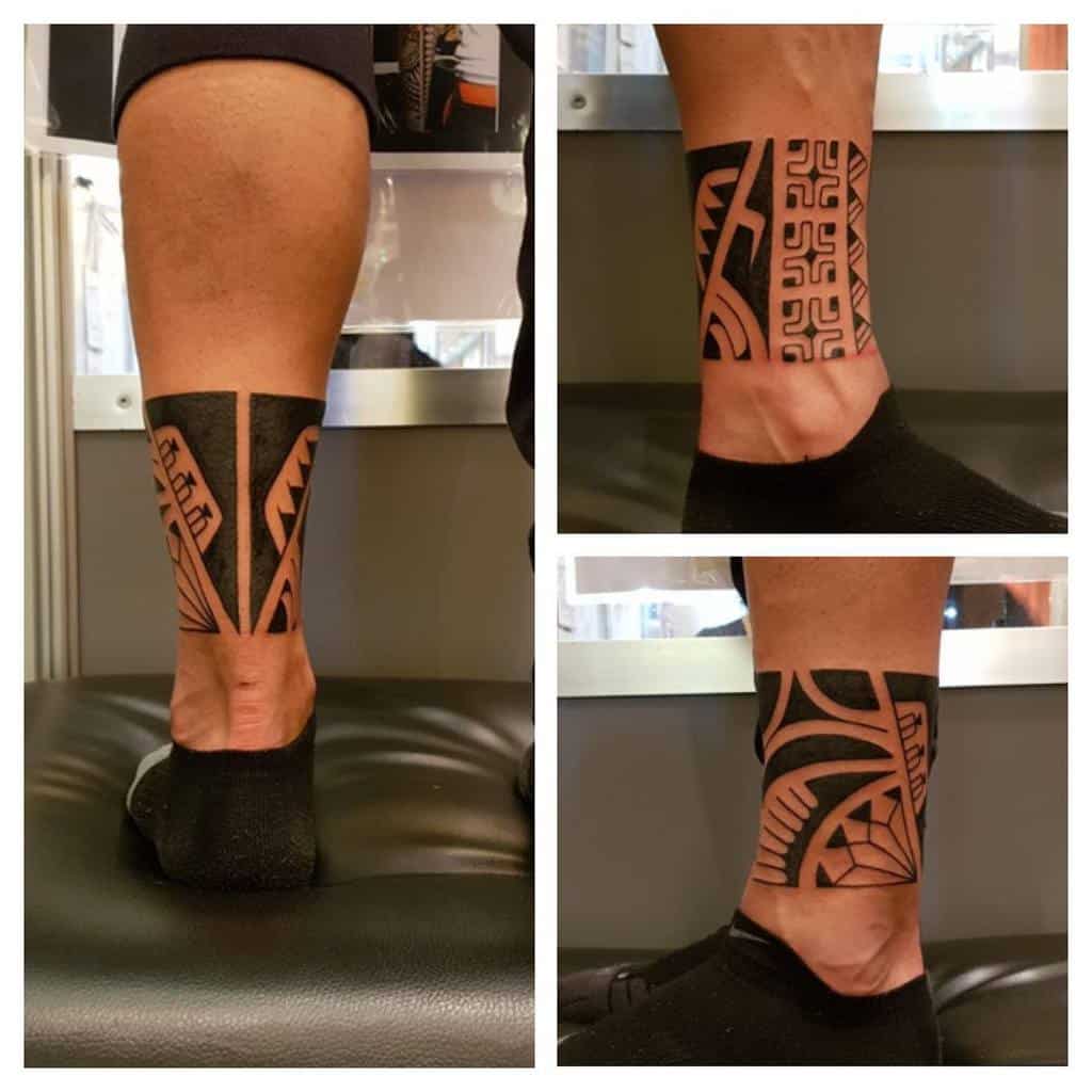 A stunning leg tattoo featuring intricate tribal patterns in black and brown ink, seamlessly blending geometric designs for a bold statement
