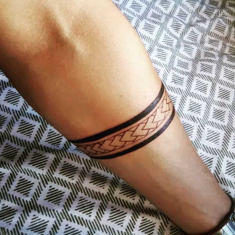 Leg adorned with a tribal-inspired double black band tattoo featuring a chevron pattern