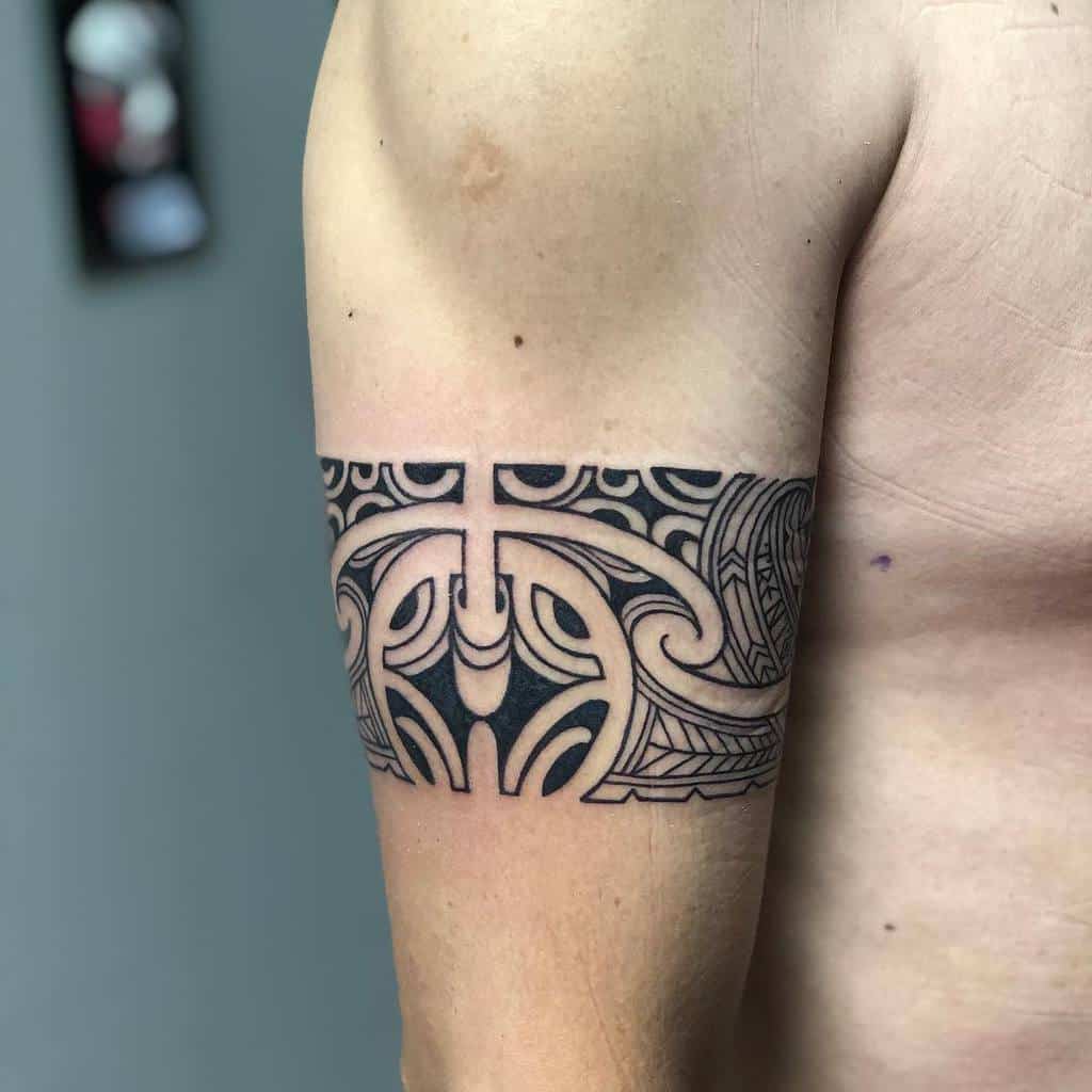 A striking tribal tattoo adorns a person's upper arm, boasting an intricate black geometric design that embodies cultural artistry