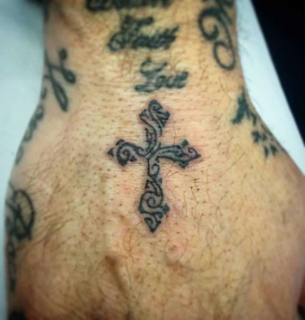 A decorative cross tattoo adorns the hand