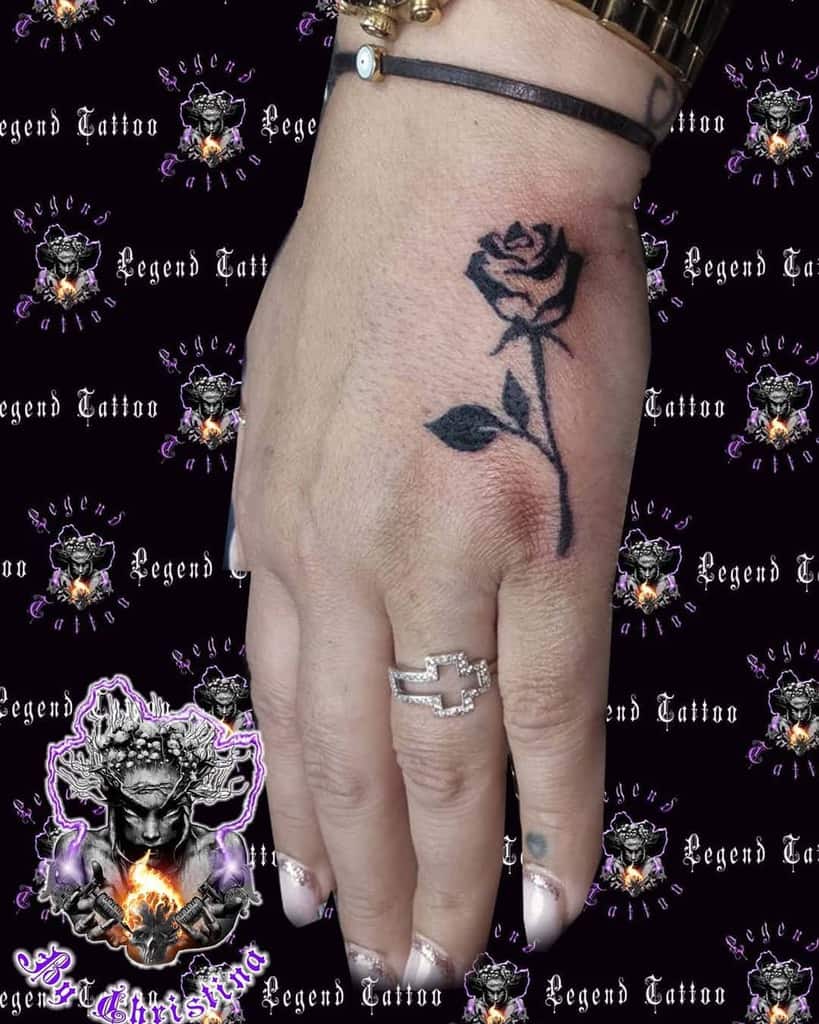 Hand tattoo of a black rose with a stem and leaf