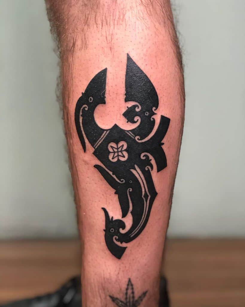 A stunning black tribal tattoo elegantly sprawls across the person’s leg, showcasing intricate patterns that captivate the eye