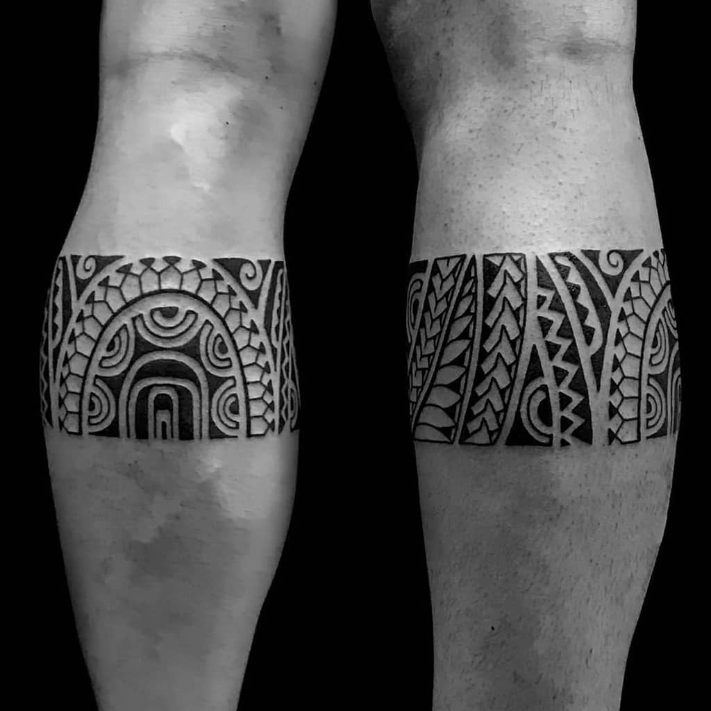 Black and white tribal tattoo bands wrap around both legs, creating a striking visual statement