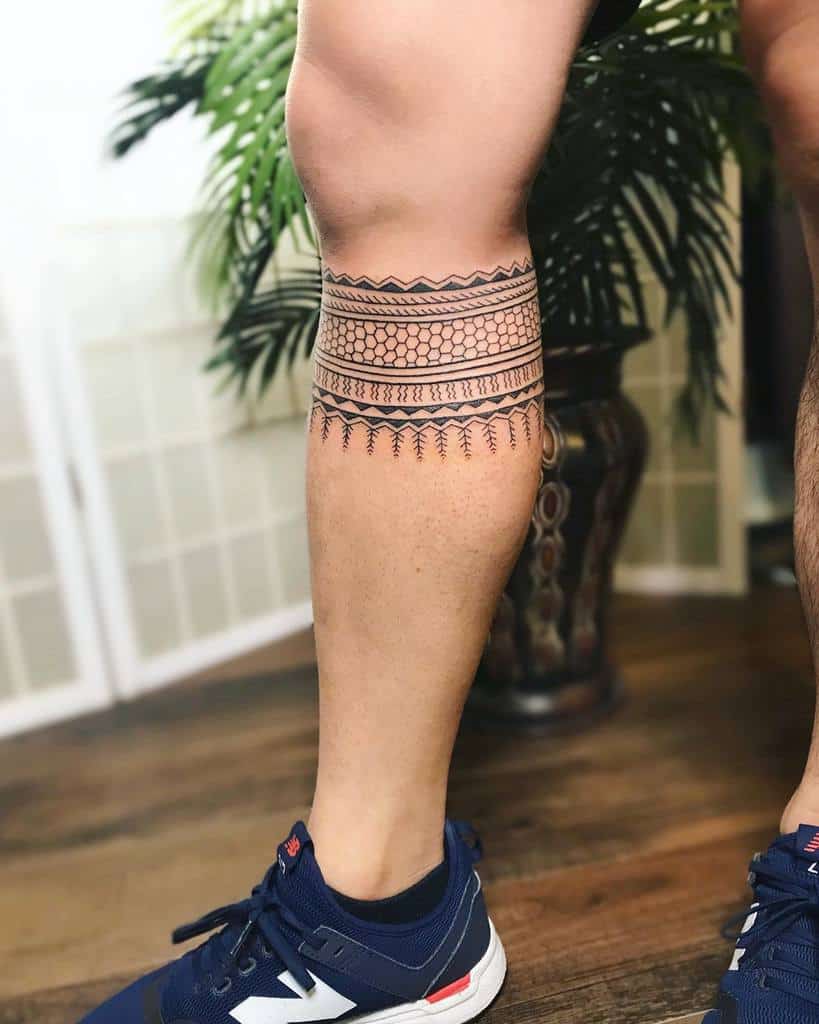 The tattoo features bold tribal patterns wrapping around the leg, with geometric shapes and lines creating a striking, symmetrical design around the calf
