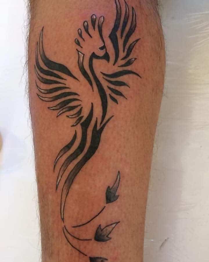 A small tattoo of a stylized phoenix in black ink graces a person's forearm