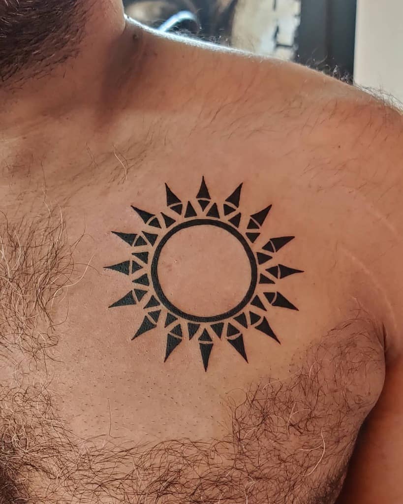 Tattoo of a sun with a circular center and triangular rays on a chest