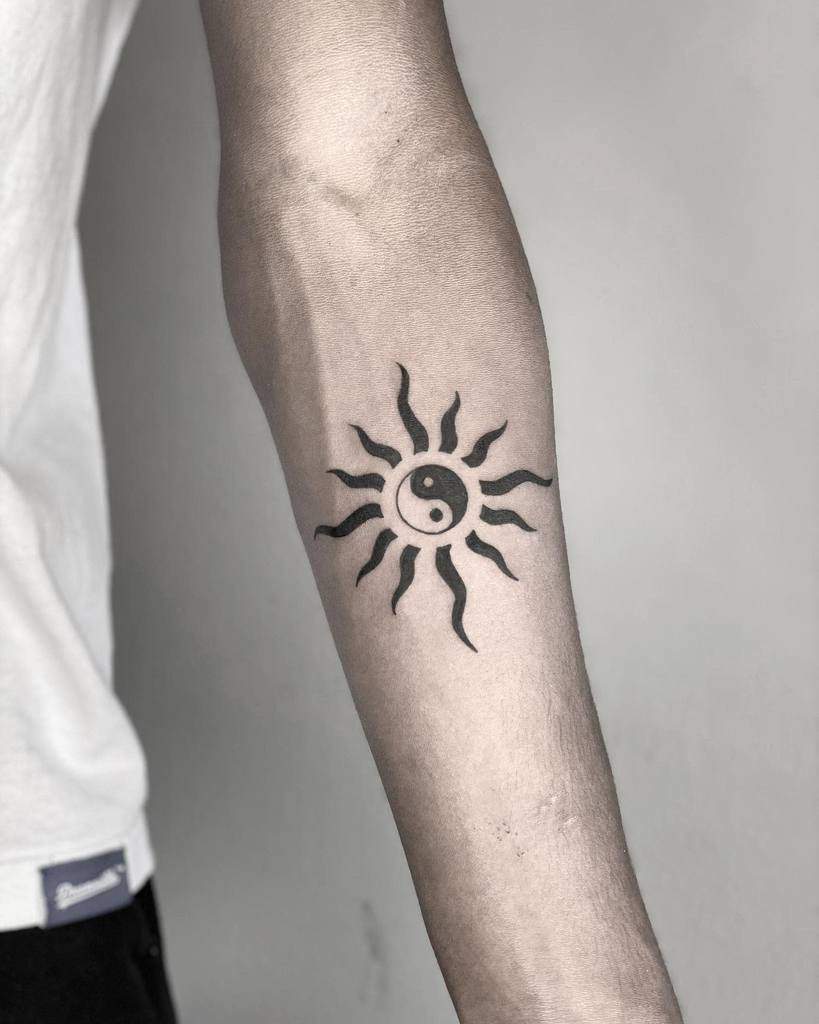Arm tattoo with a sun design featuring a yin-yang symbol in the center