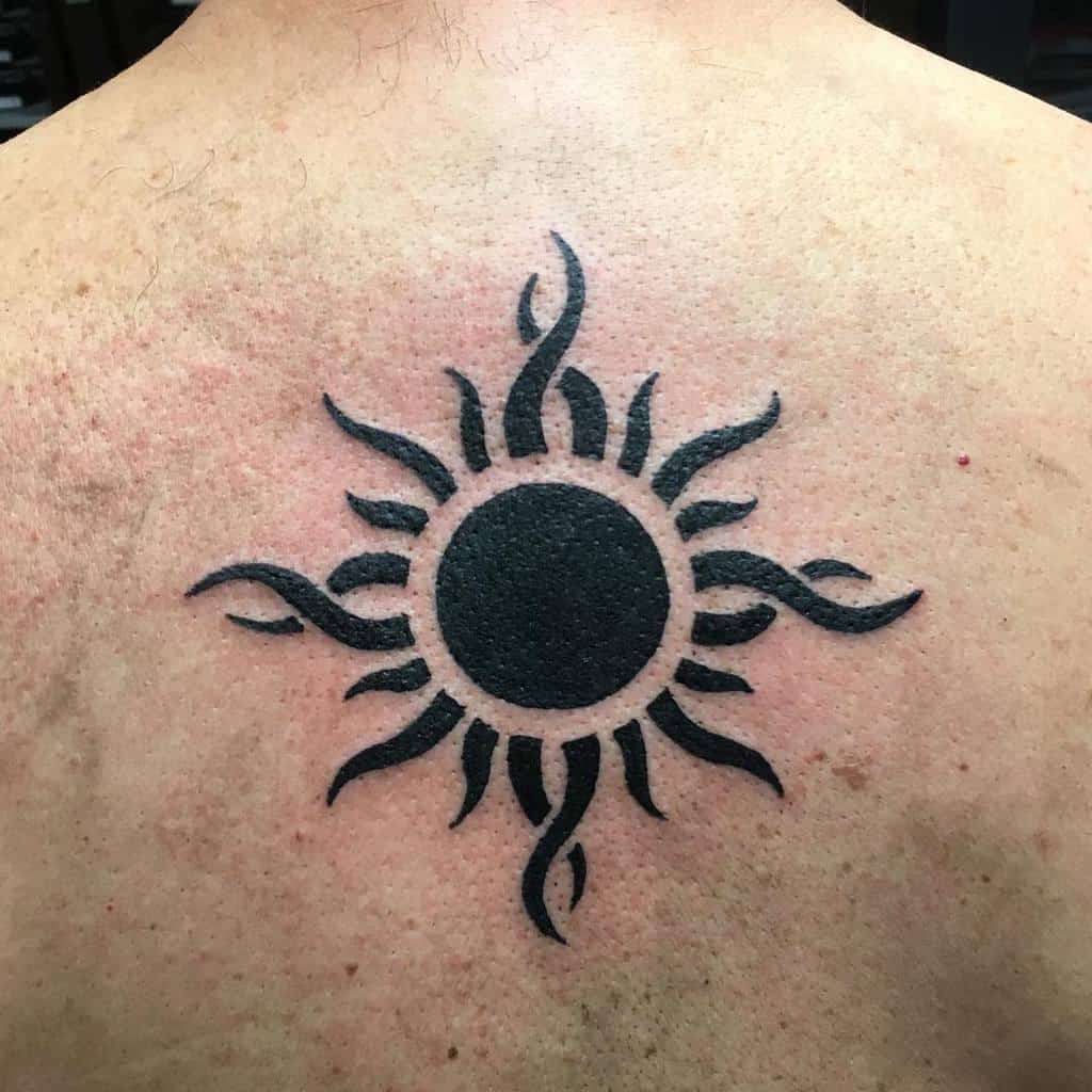 Sun-shaped tattoo with flame-like rays on a back
