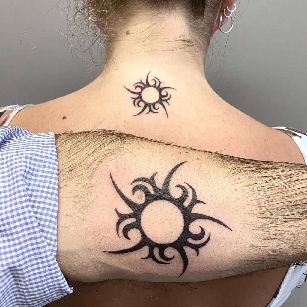 Matching sun tribal tattoos on two individuals' neck and arm