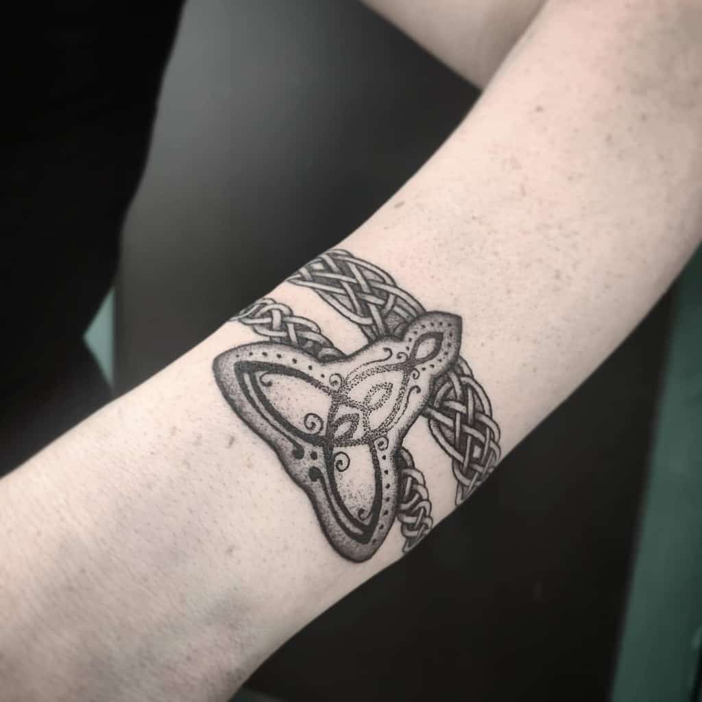 Celtic knot tattoo with intricate triquetra design on forearm, shaded in black and gray