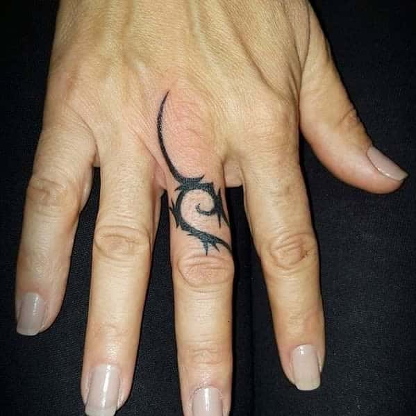 Hand with a black tribal tattoo on the middle finger