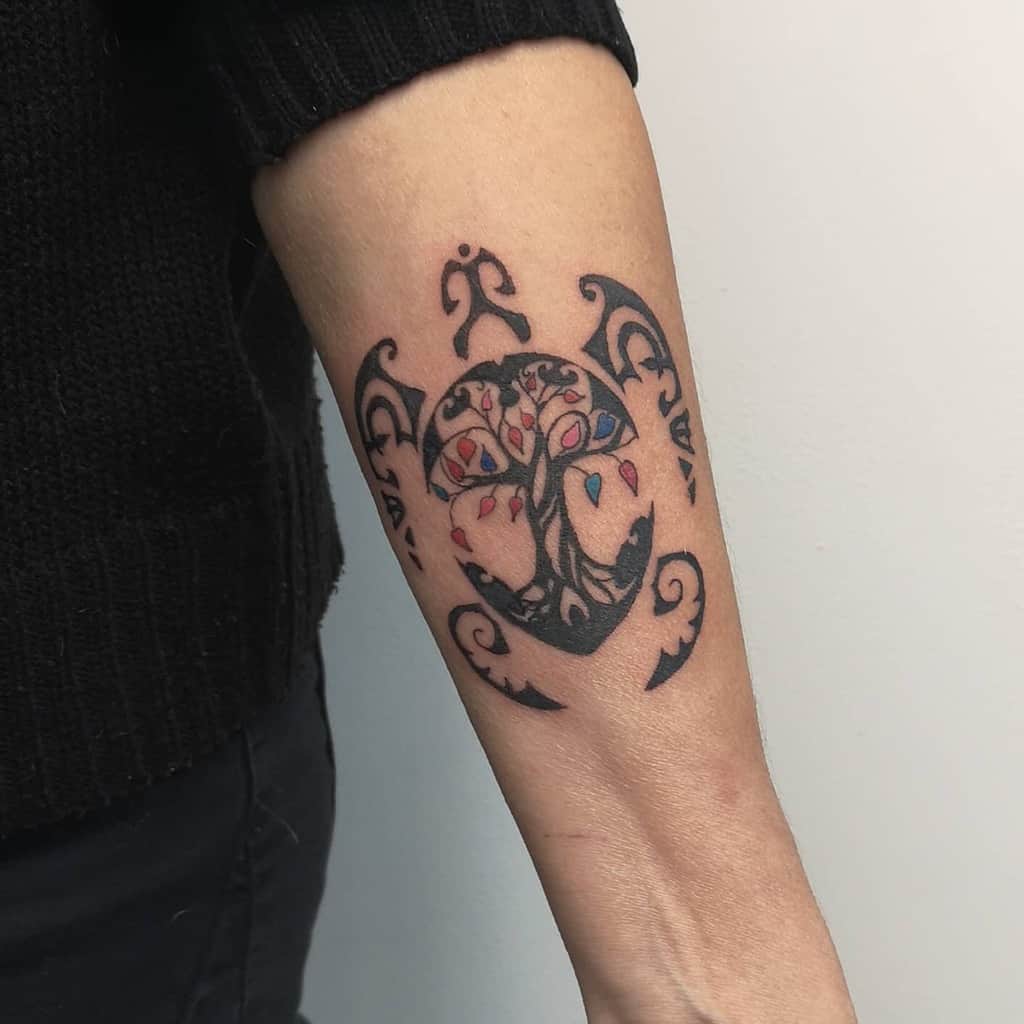 Arm tattoo of a tribal turtle with a tree design inside