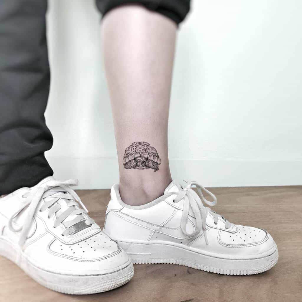 A small black ink tattoo of a detailed turtle on the ankle
