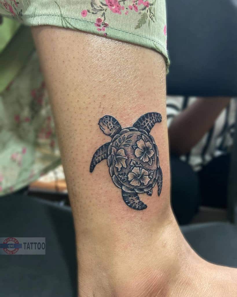 Turtle tattoo with floral design on a leg