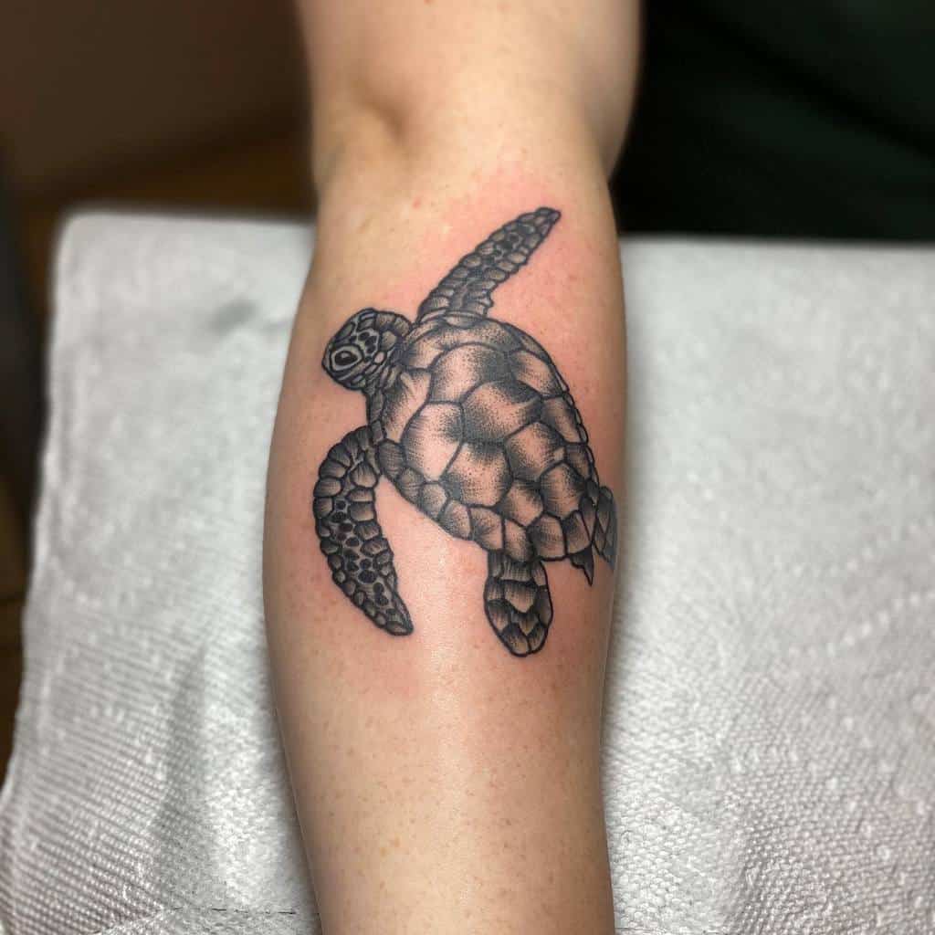 Black ink tattoo of a sea turtle on a forearm