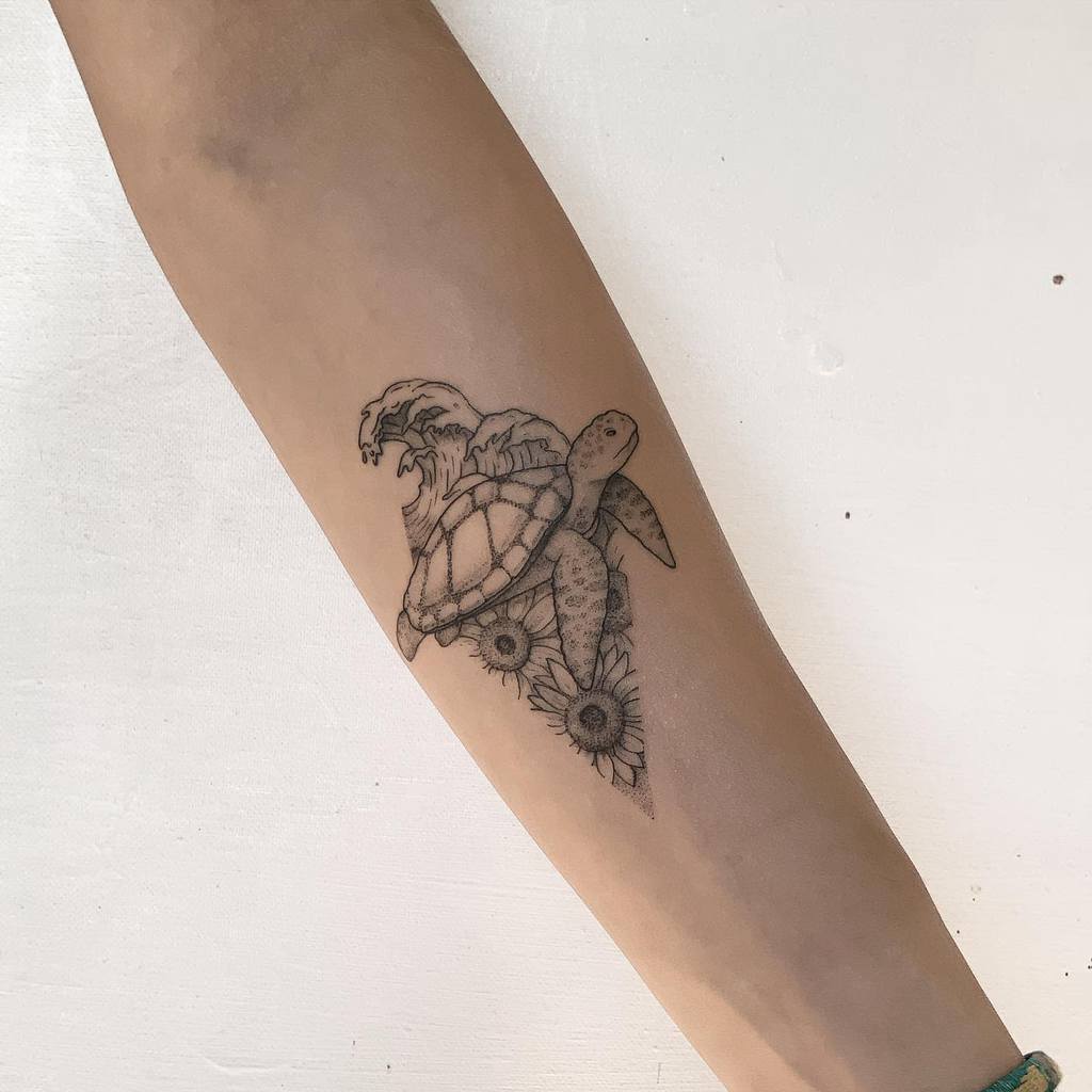 Arm tattoo of a turtle with sunflowers, waves, and a mountain design