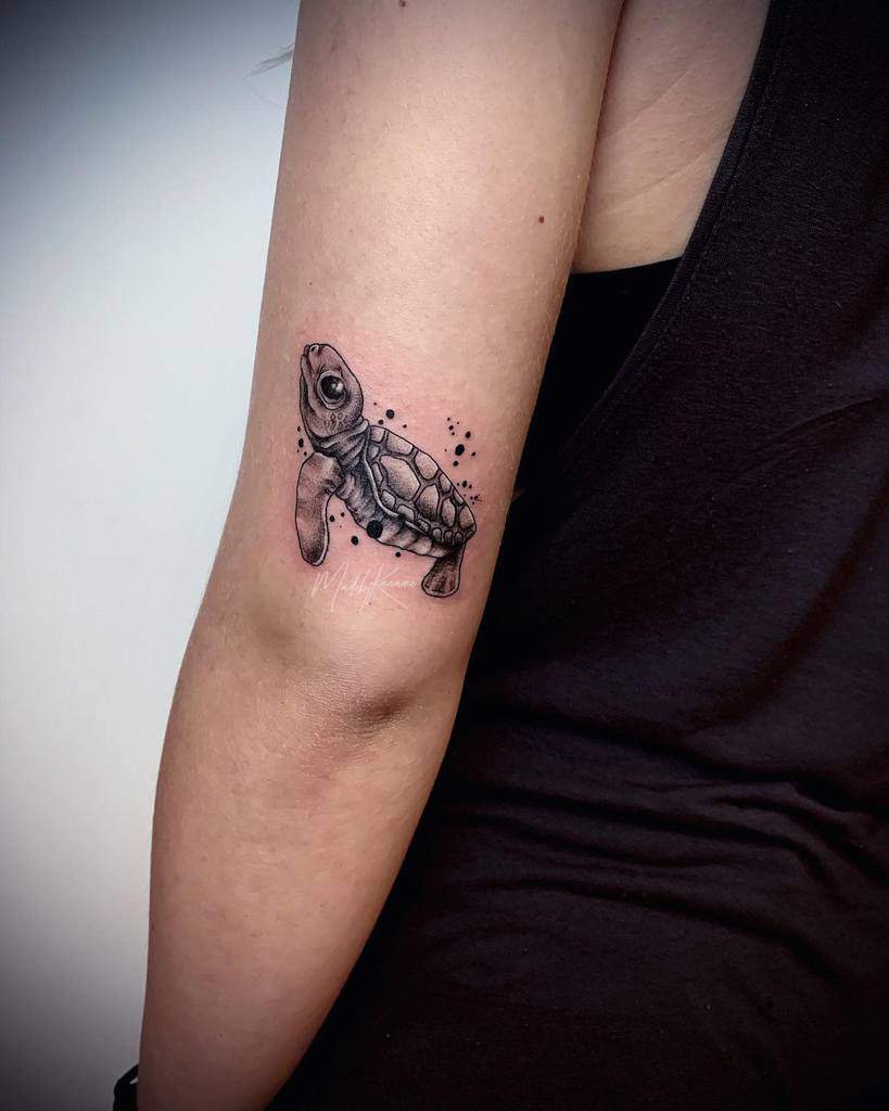 A small sea turtle tattoo on an upper arm