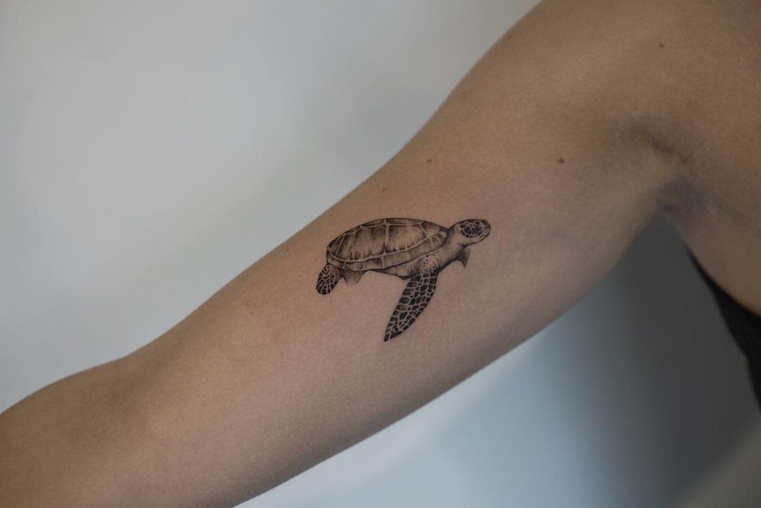A small sea turtle tattoo on an upper arm