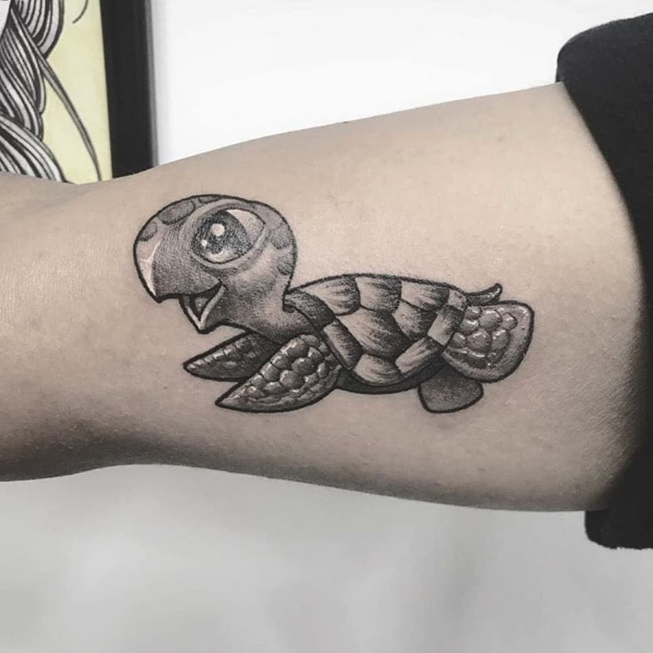 A cartoon-style turtle tattoo on an upper arm