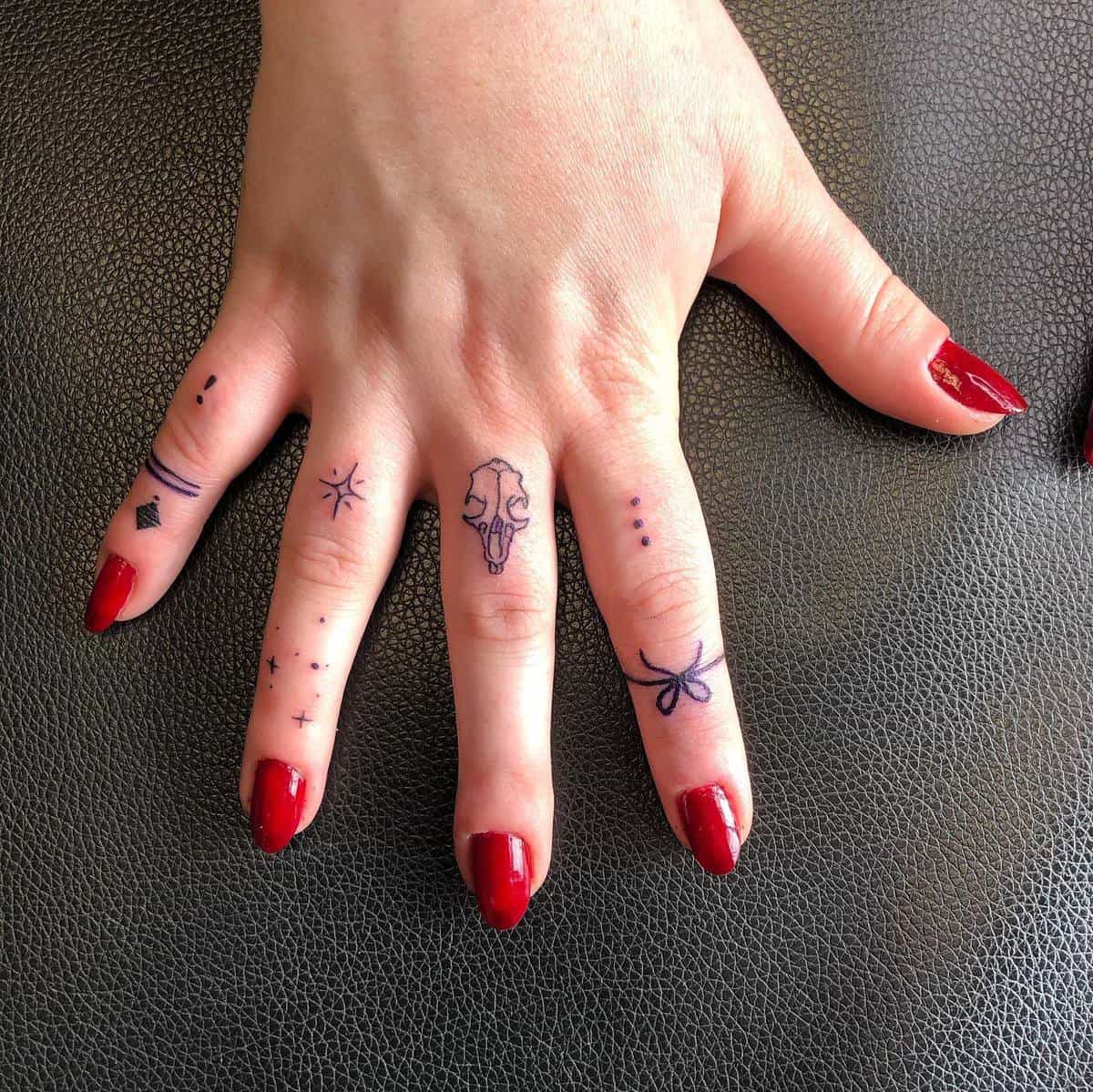 Minimalist witchy symbols, including a skull and stars, tattooed on fingers