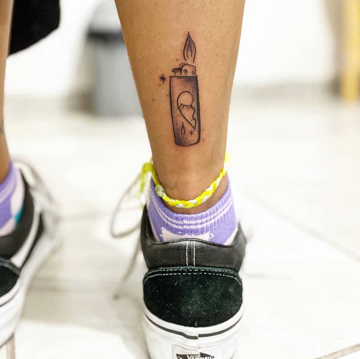 Leg tattoo of a lit lighter above an anklet