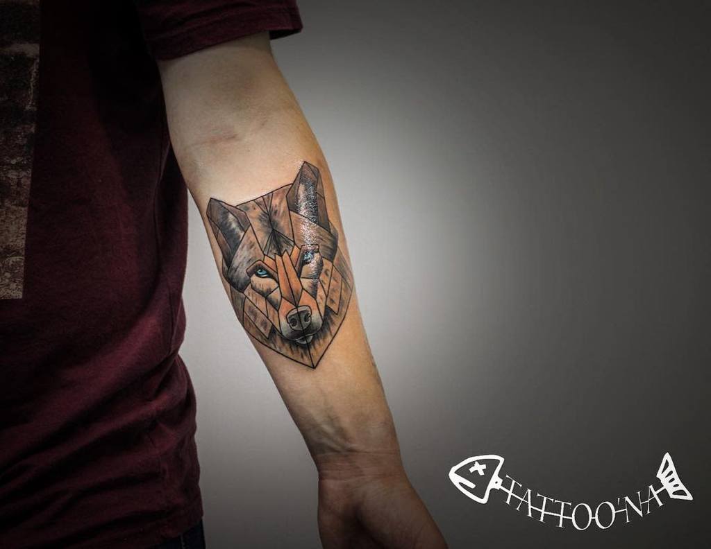 The geometric wolf tattoo graces the forearm with vibrant colors and sharp lines, showcasing a stunning blend of artistry and nature