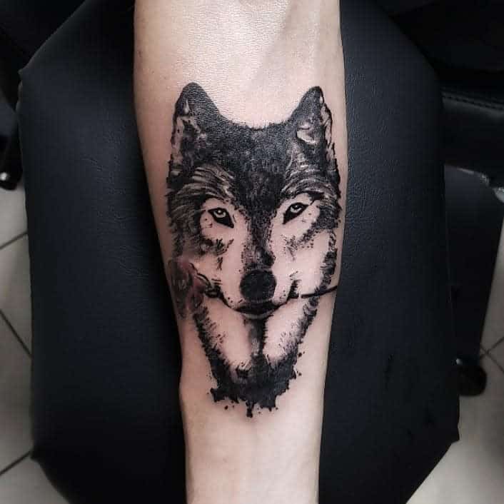 A striking tattoo of a wolf's intense gaze graces a person's arm, skillfully shaded in black and gray ink