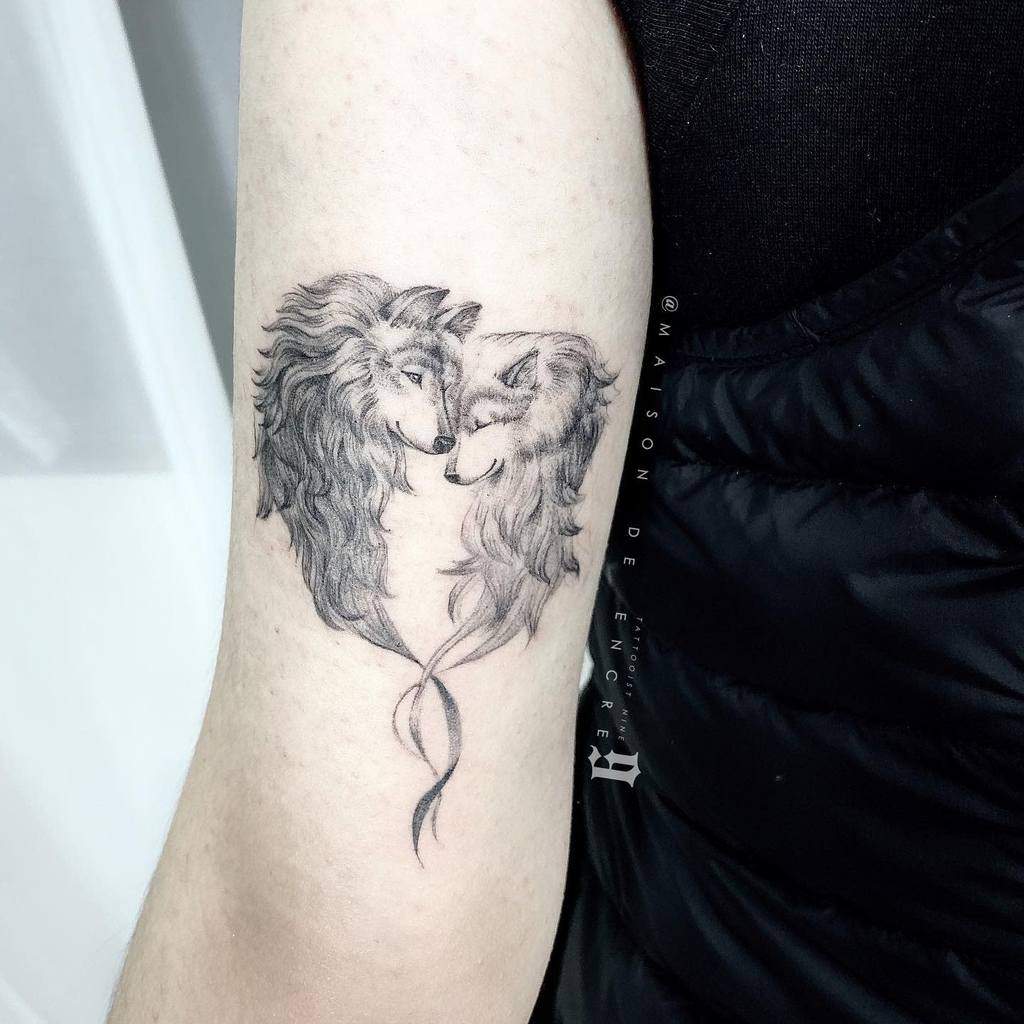 Tattoo of two majestic wolves intricately forming a heart shape on an arm
