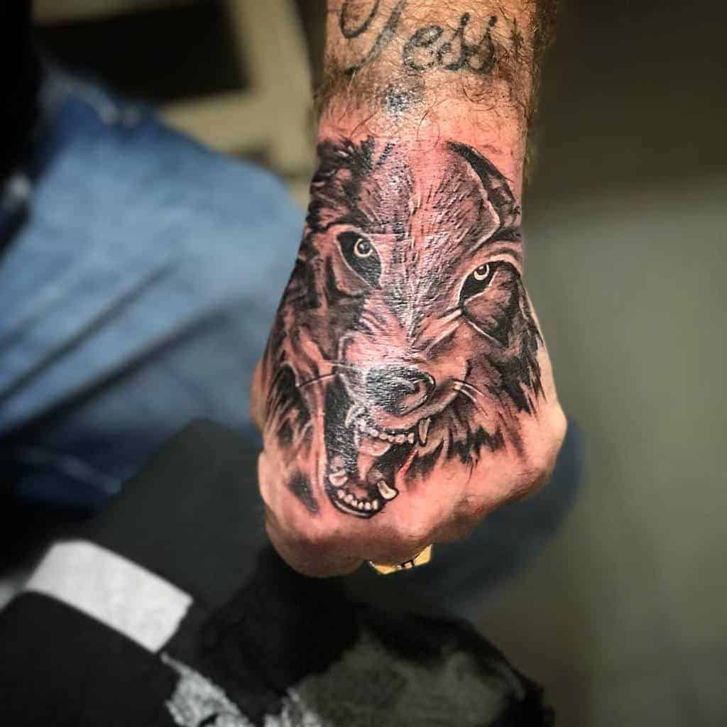 A striking tattoo of a fierce, snarling wolf graces the back of a hand