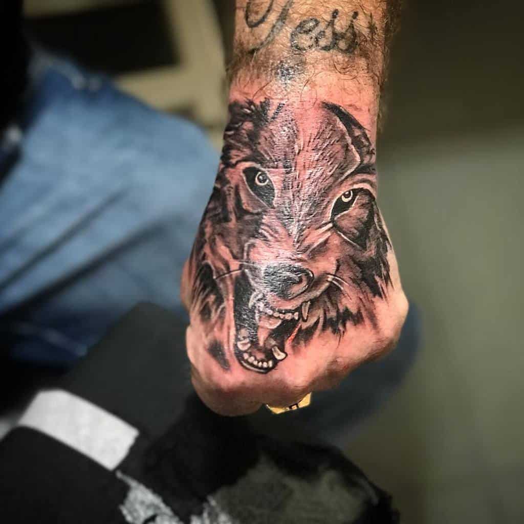 A tattoo of a fierce, snarling wolf etched onto a person's hand commands attention, embodying untamed spirit and raw strength