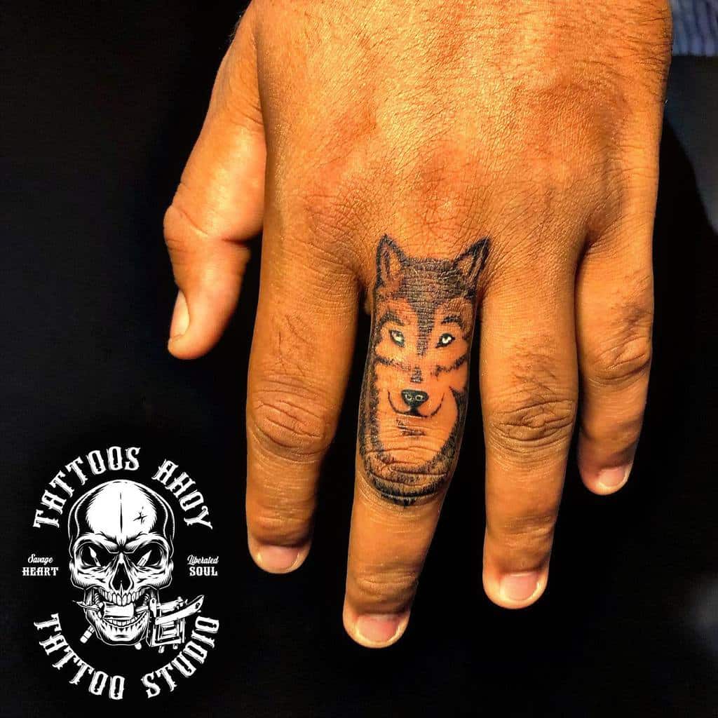 A hand showcases a striking wolf tattoo etched onto the finger