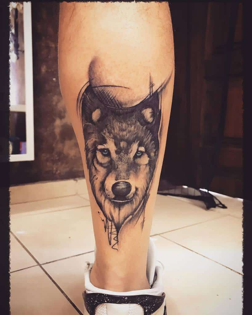 Realistic wolf tattoo on the calf with abstract shading and sharp line accents for a bold, artistic design