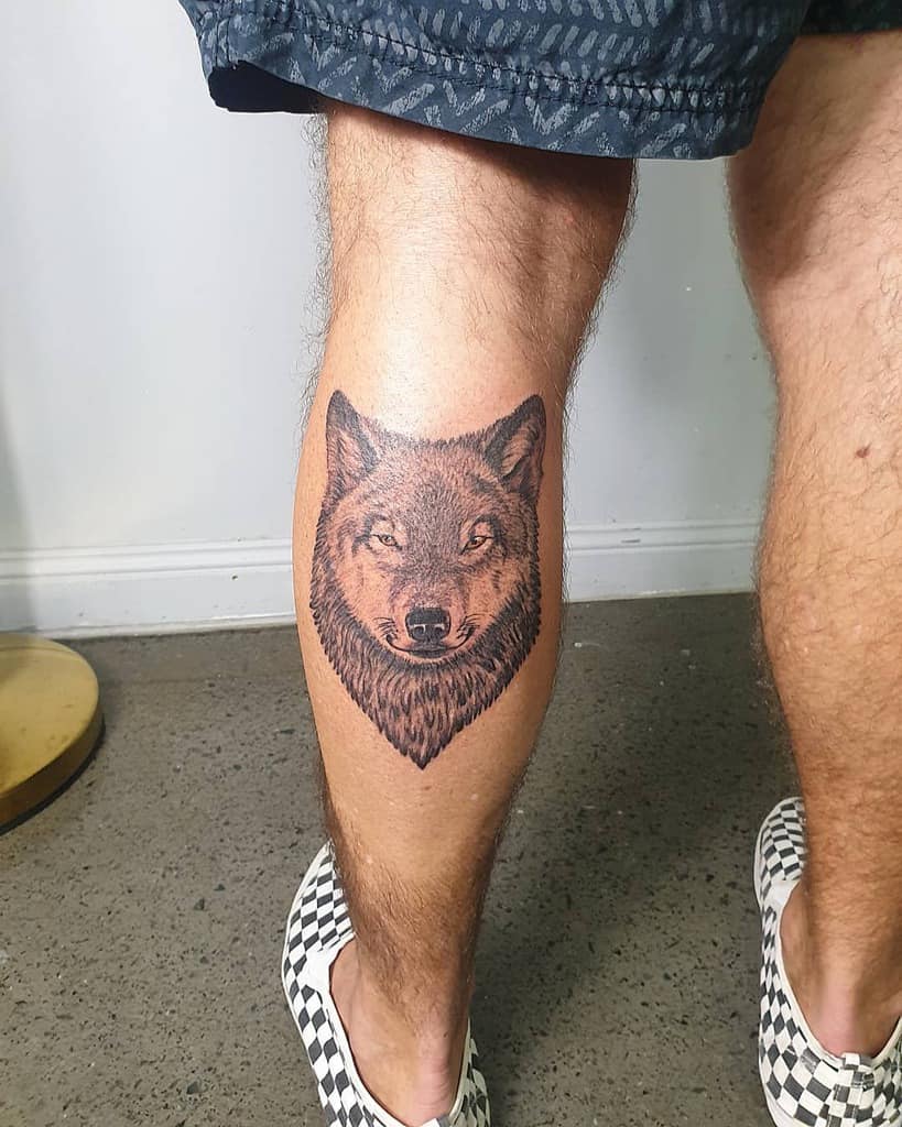 A stunning wolf tattoo graces the back of the person's leg