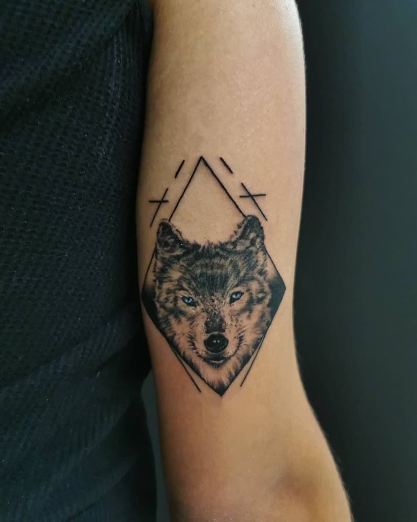A captivating wolf, intricately woven into geometric shapes, adorns a person's arm with striking detail