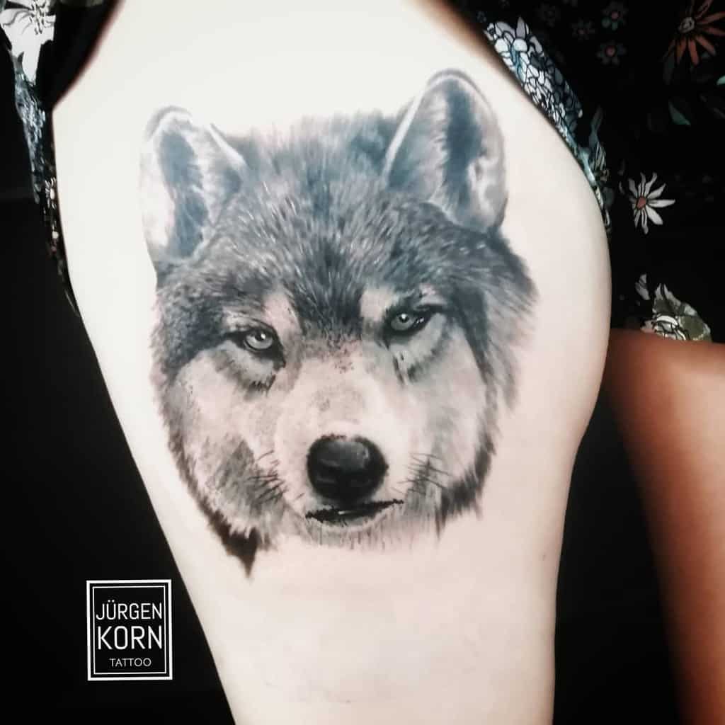 A detailed wolf tattoo prowls across the upper thigh