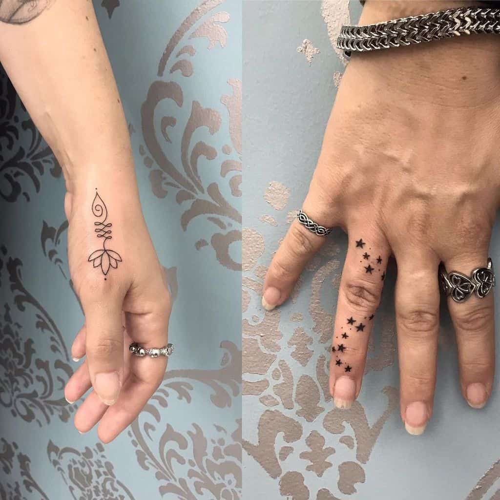 Two hands with tattoos; one has a floral design, the other features small stars on the finger