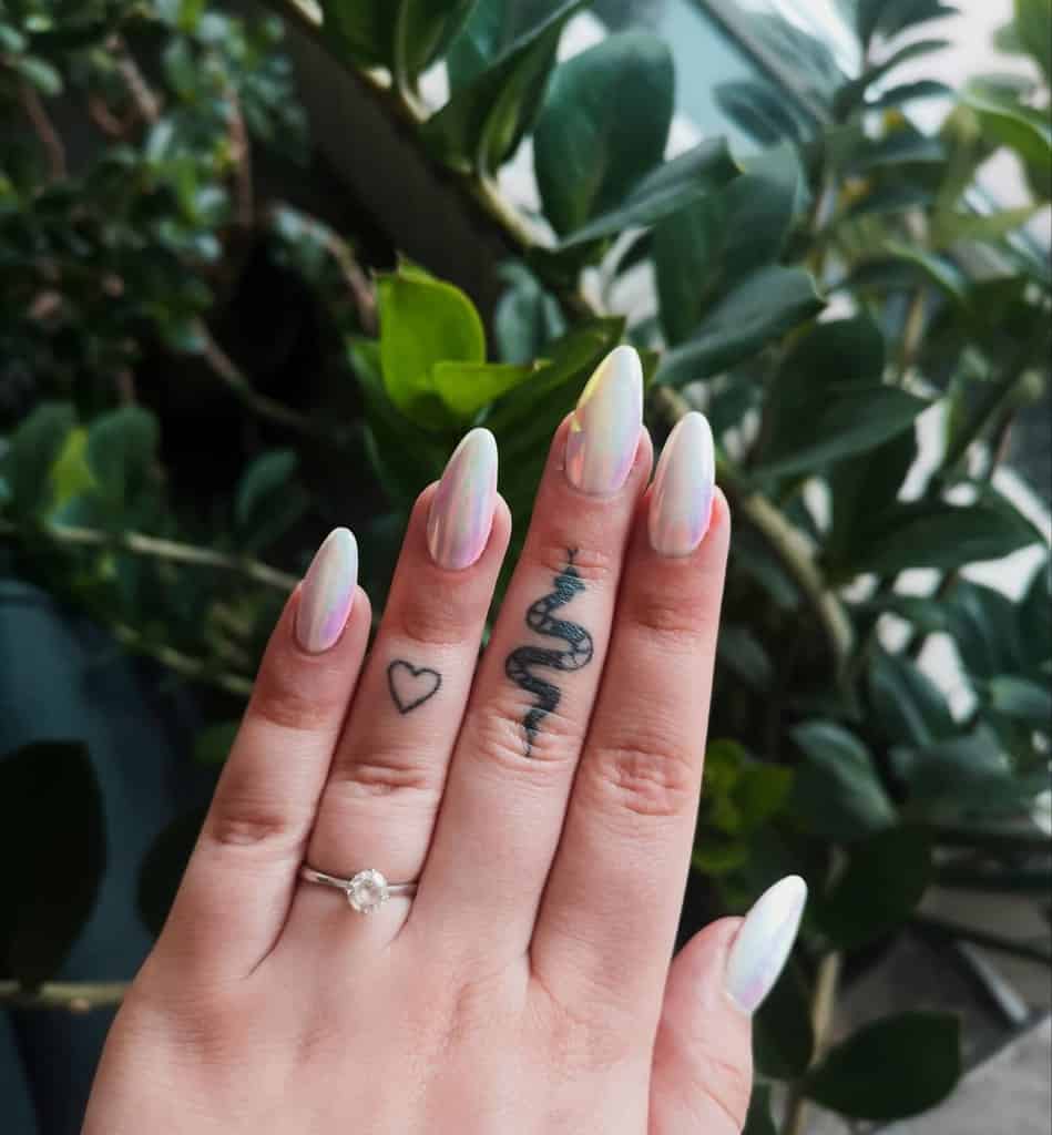 Hand with heart and snake tattoos on the fingers