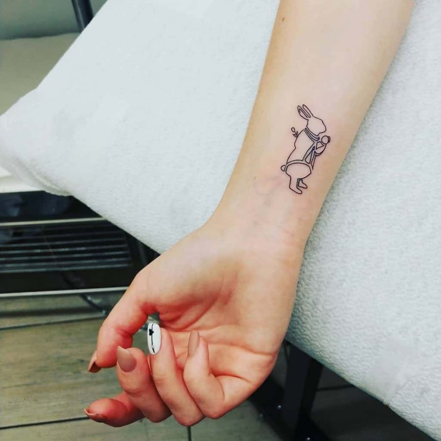 Simple outline tattoo of a bunny on a person’s wrist