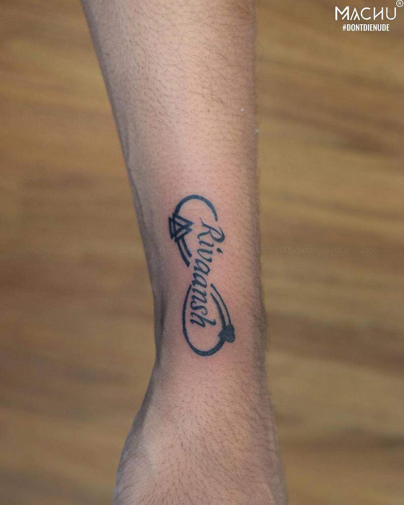 Elegant wrist tattoo featuring the name 'Rivaansh' in cursive script, adorned with a heart and diamond-like design for a personalized touch