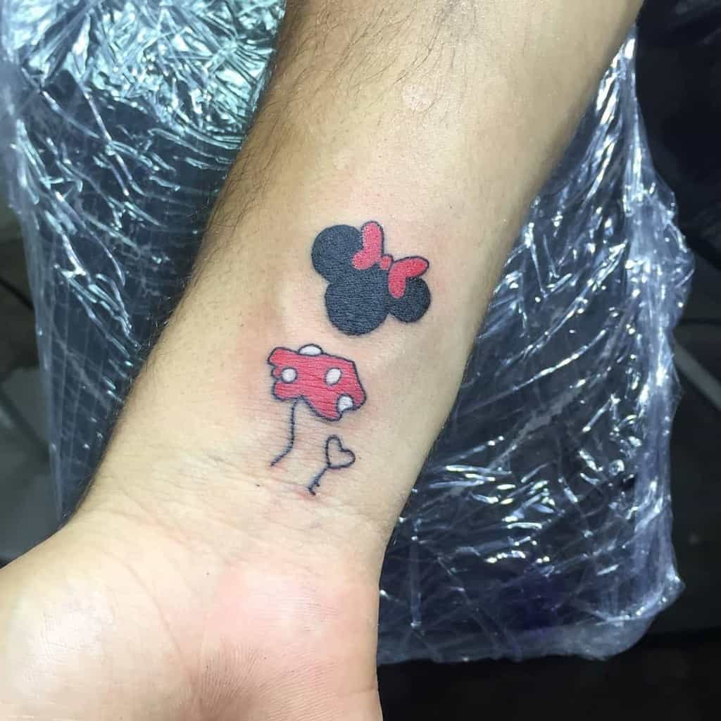 Tattoo of Minnie Mouse ears and a red bow above a red and white polka-dotted heart-shaped mushroom