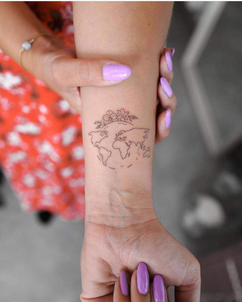 Minimalist world map wrist tattoo with delicate floral details on top, symbolizing travel, adventure, and a love for exploration