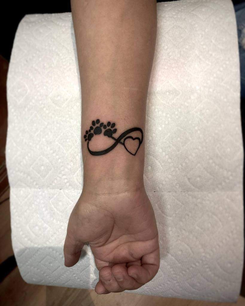 Wrist tattoo with paw prints, an infinity symbol, and a heart design