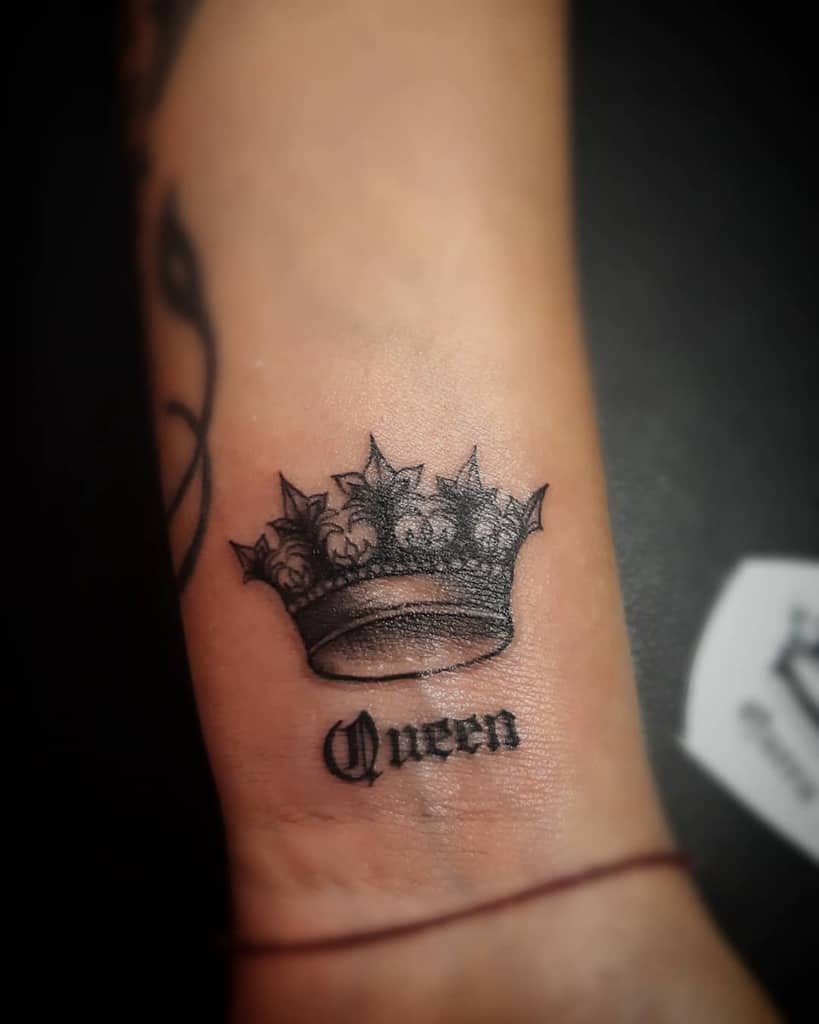 A tattoo of a crown with the word "Queen" beneath it on a wrist
