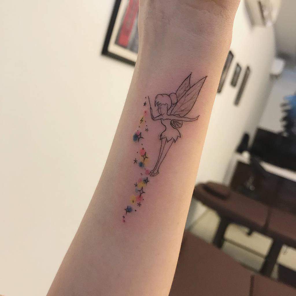 Tattoo of a fairy blowing colorful stars on a wrist