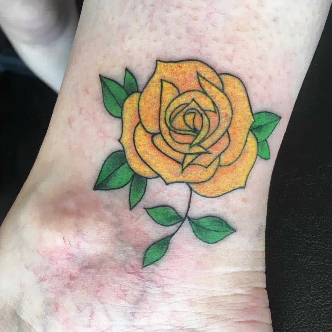 Yellow rose tattoo with green leaves on lower leg and foot
