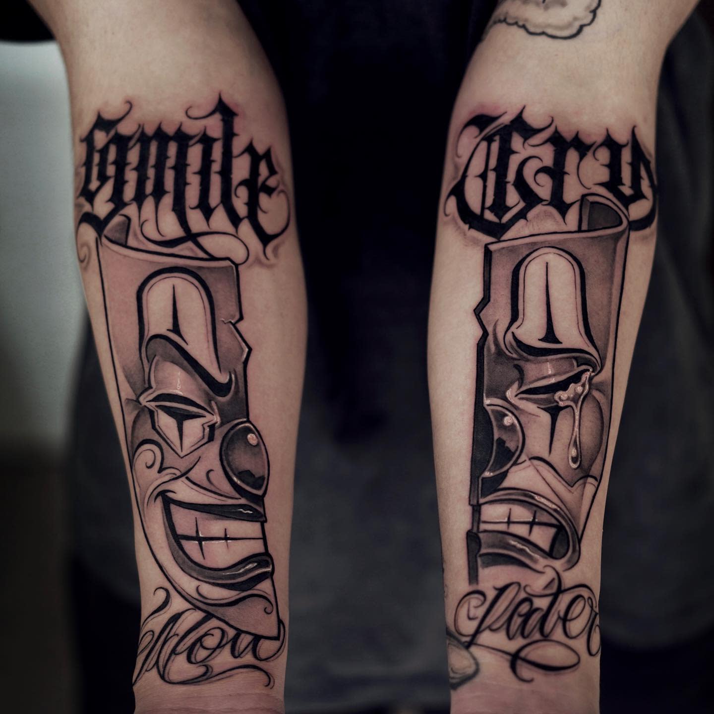 Forearm tattoos featuring a smiling clown on the left and a crying clown on the right