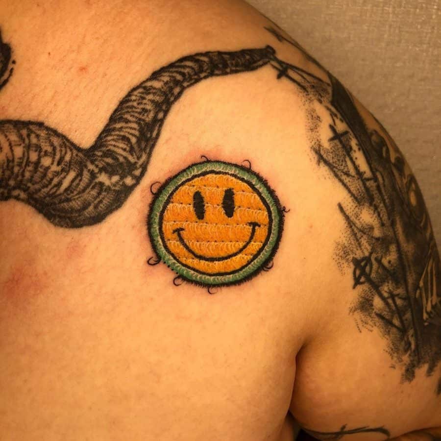 Retro-inspired embroidery tattoo of a smiley face, designed with detailed threadwork and a slightly distressed patch look.